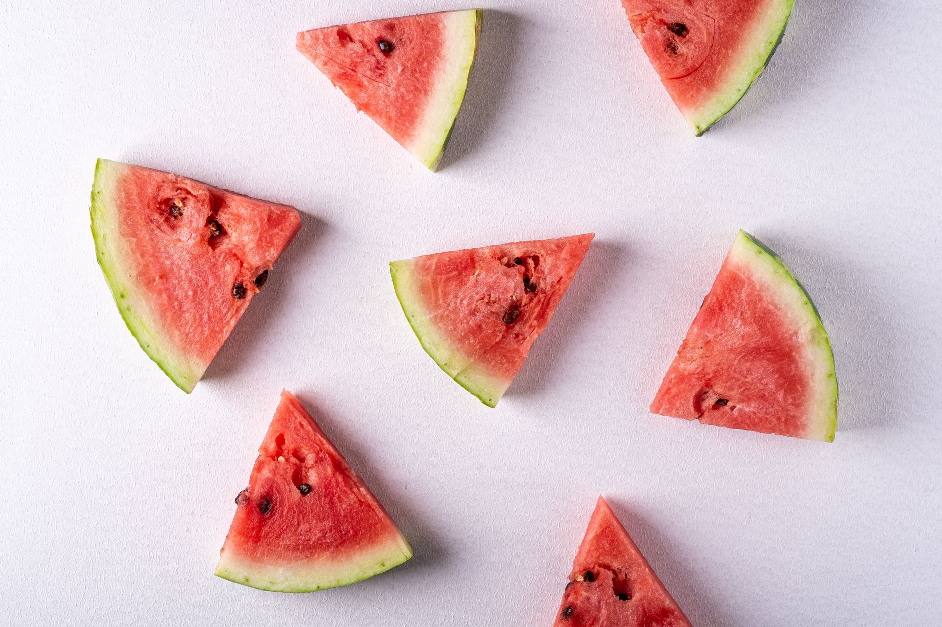 Sliced watermelon arranged beside skincare bottles and a dropper on a light countertop