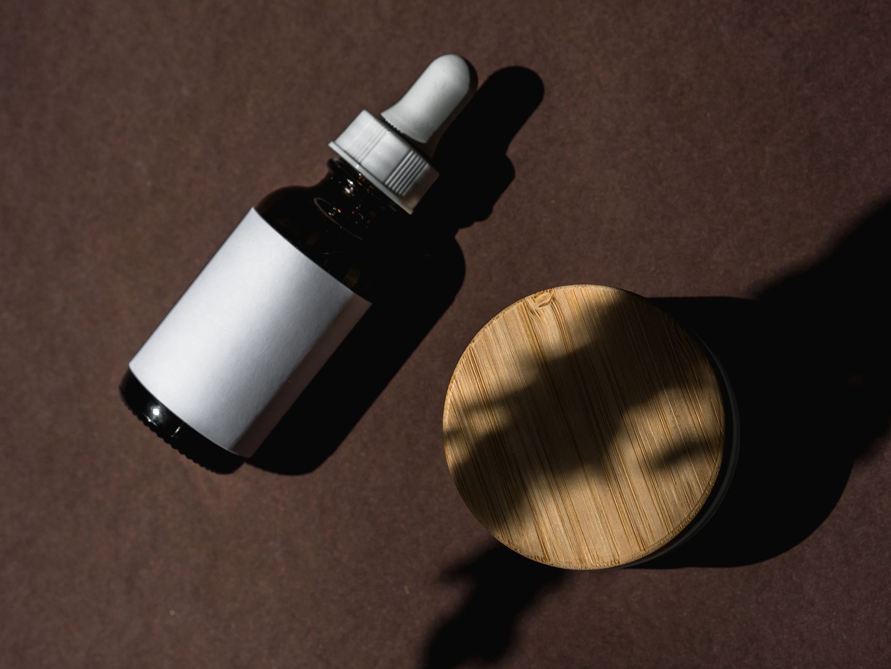 A jar of solid rendered beef tallow beside a small skincare spatula on a bathroom counter